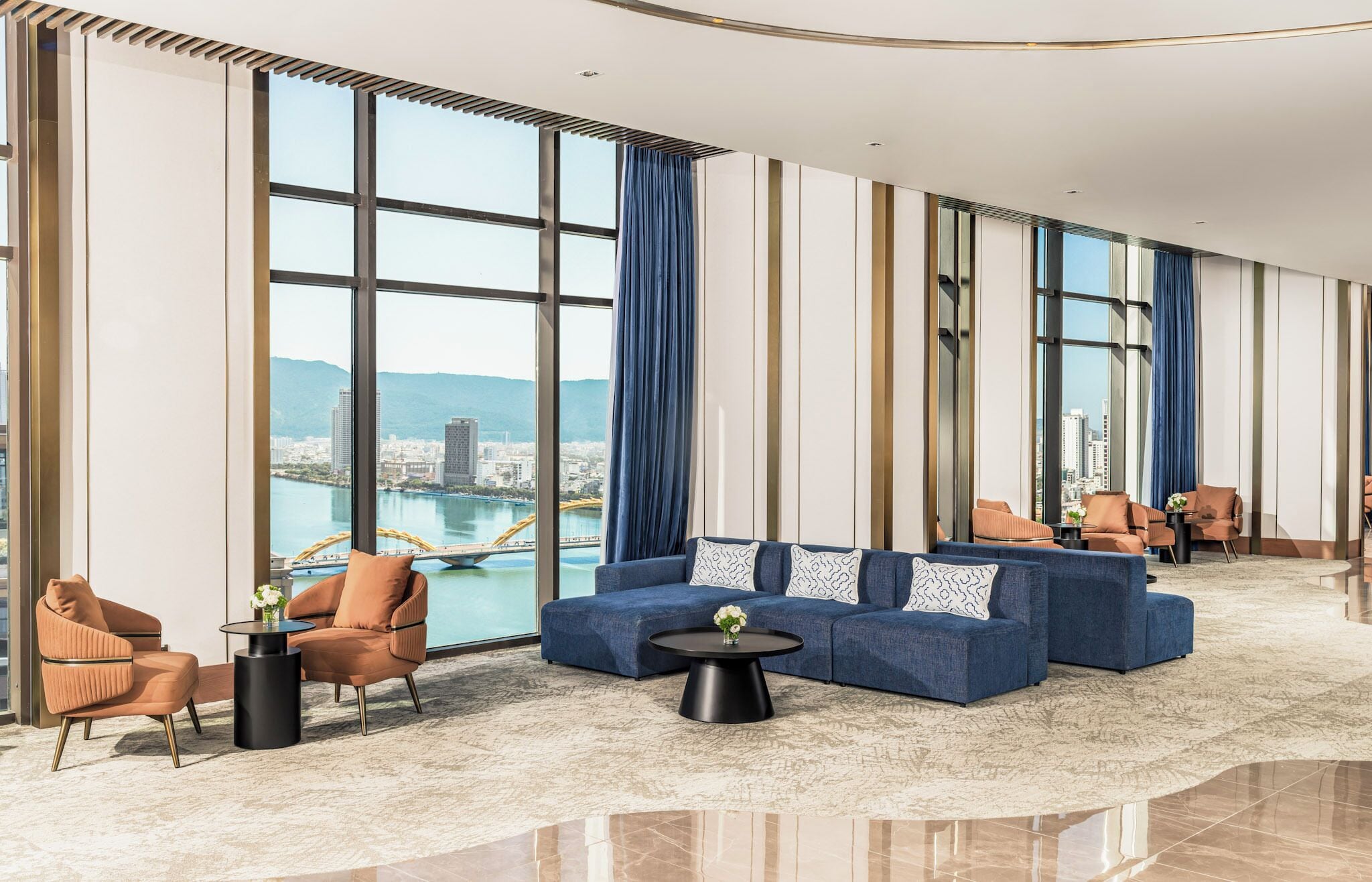 Un amplio vestíbulo de hotel con una gran zona de estar, vistas a la ciudad y un diseño moderno.