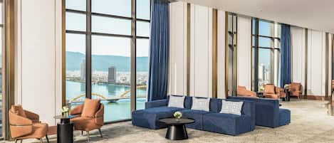 Un hall d’hôtel spacieux, doté d’un grand espace salon, offrant une vue sur le paysage urbain et présentant un design moderne.
