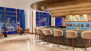 A bar area with a city view, bar stools, and a bar counter. - TUI BLUE Han River (Da Nang)