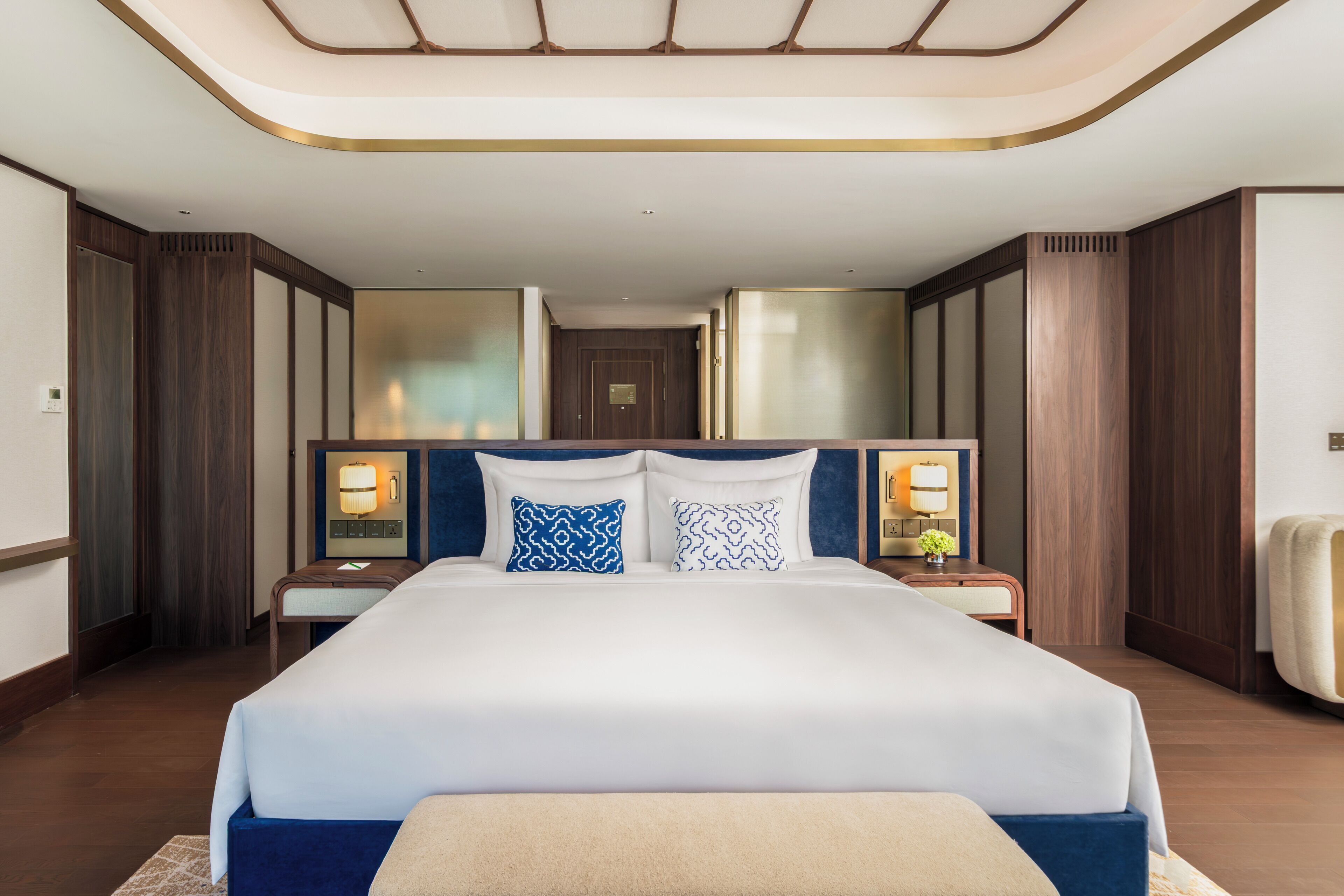 Een hotelkamer met een groot bed, twee nachtkastjes, een hoofdeinde en een plafondlamp.