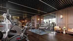 A modern gym with various exercise equipment, wooden paneling, and a large window providing natural light. - TUI BLUE Han River (Da Nang)