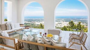 A modern outdoor seating area with a city view, featuring a sofa, chairs, and a glass table. - Villa Eterea - Five Bedroom Villa, Sleeps 10 (Selva di Fasano)