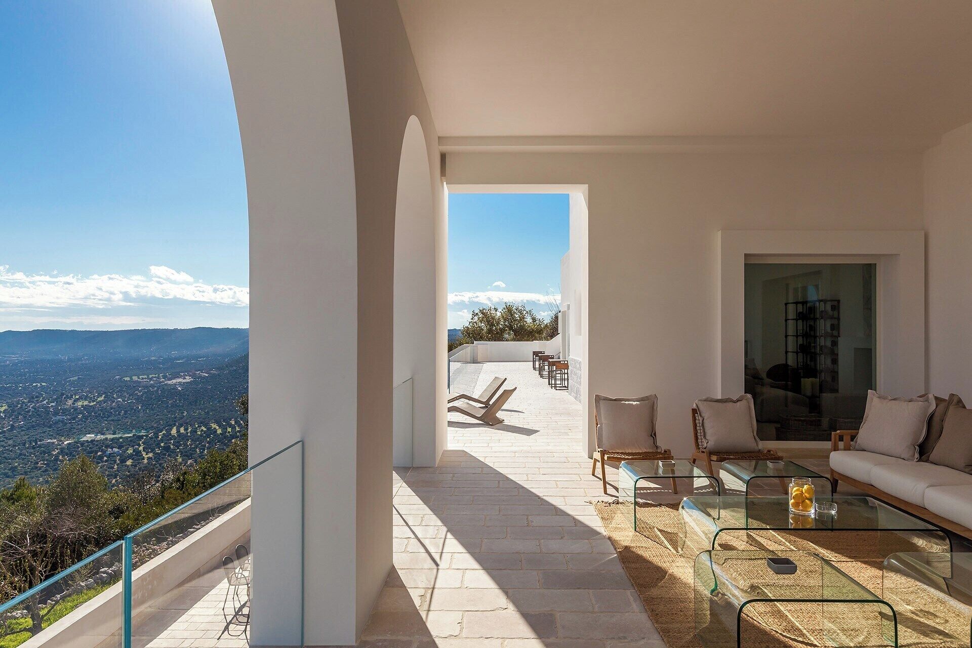 Een modern balkon met helder uitzicht op het landschap, voorzien van een bank, stoelen en een glazen tafel.