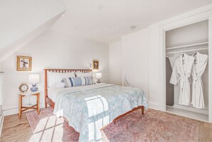 Ein Schlafzimmer mit Bett, Nachttischen, einer Kommode und einem Kleiderschrank sowie einer Garderobenstange.