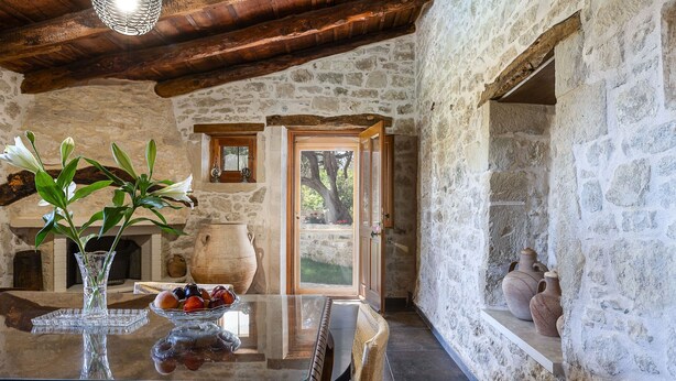 A rustic stone interior with a wooden table, a vase with flowers, and a bowl of fruit. - Laga 1577 Traditional Stonehouse, a cozy retreat (Laga)