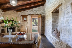 A rustic stone interior with a wooden table, a vase with flowers, and a bowl of fruit. - Laga 1577 Traditional Stonehouse, a cozy retreat (Laga)