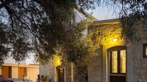 A stone building with a staircase leading to a door, potted plants, and a lantern on a stone ledge. - Laga 1577 Traditional Stonehouse, a cozy retreat (Laga)