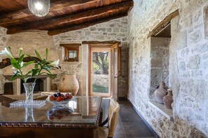 A rustic stone interior with a wooden table, a vase with flowers, and a bowl of fruit. - Laga 1577 Traditional Stonehouse (Mylopotamos)