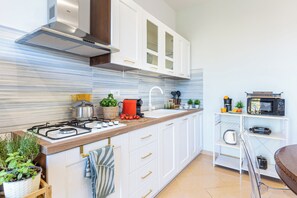 A modern kitchen with white cabinets, a stainless steel stove, and a microwave. - Chlorèa Sorrento Panoramic Apartment (Sorrento)