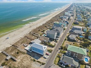 Vista aerea di una zona residenziale sulla costa, con case, una spiaggia e una strada.