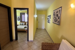 Un pasillo con una cama al fondo, una puerta y una pared decorada con cuadros.