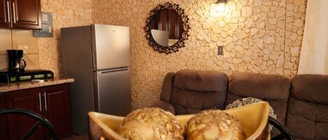 A kitchen with a stone wall, a refrigerator, a coffee maker, and a bowl of decorative items.