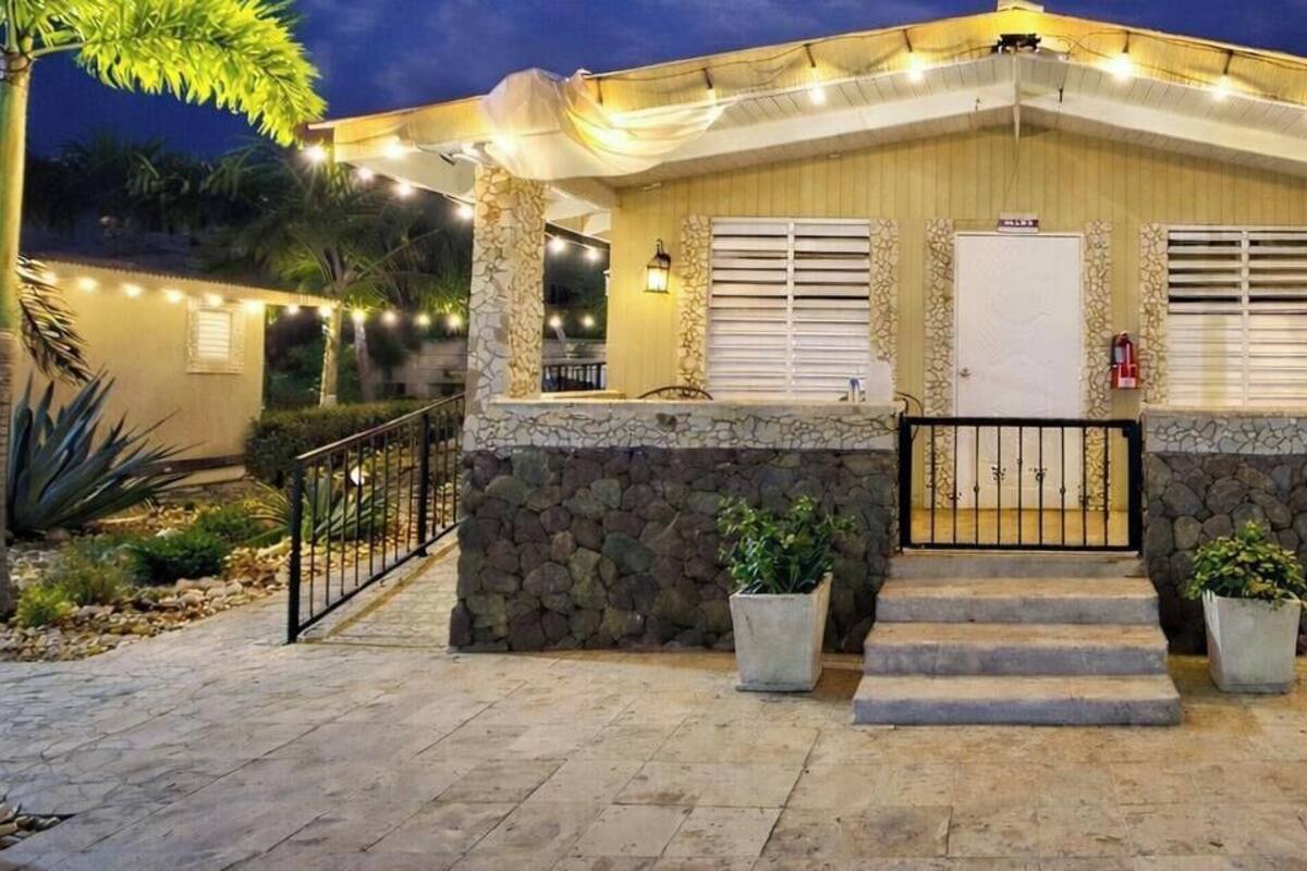A house with a stone facade, a front door, and a small porch with string lights.