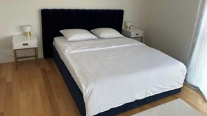 A neatly made bed with white bedding, a dark headboard, and two bedside tables with lamps. - Stylish 2.5-Room + Basel Card | 6th-Floor Comfort (Basel)