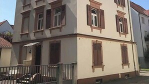 A multi-story building with a symmetrical facade, featuring evenly spaced windows with shutters, a central entrance, and a visible antenna on the roof. - 1st Central 2 BR w/ Living room + 5mn from Basel (Saint-Louis)