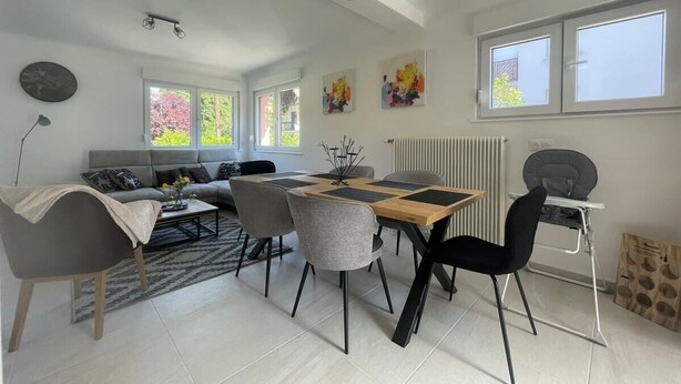A modern living room with a dining area, a sofa, a coffee table, and a baby changing station.