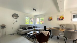 A modern living room with a sofa, coffee table, and dining area with chairs.