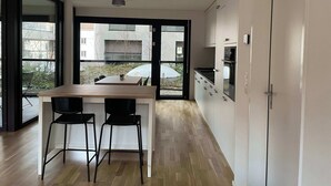 A modern kitchen with a wooden dining table and two chairs, large windows, and a view of the outside. - Perfect connected to Downtown, Airport & Highway (Basel)