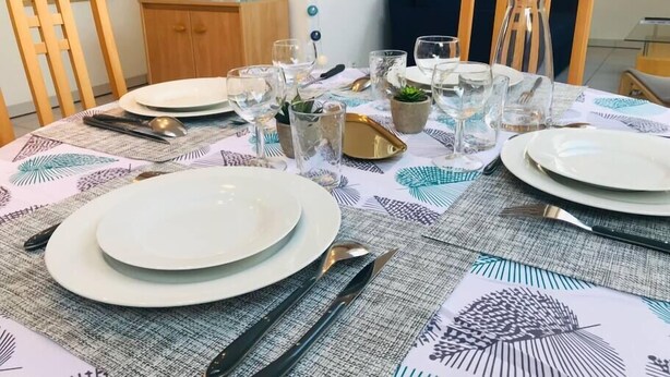 A dining table set with plates, cutlery, and glasses, surrounded by chairs and a small cabinet. - 3rd Central 1 BR w/ 3 single beds 45m2 + 5mn from Basel (Saint-Louis)
