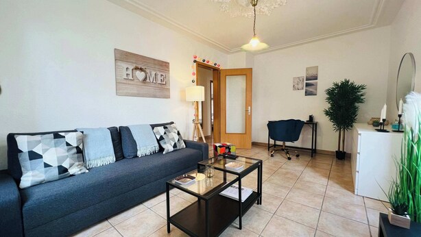 Un salon comprenant un canapé, une table basse, une lampe et une porte donnant sur une autre pièce.