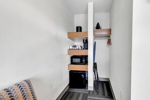 A narrow hallway with a microwave, coffee maker, and a small refrigerator on a shelf. - Holiday Shores King Bed (Myrtle Beach)