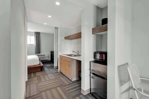 Ein modernes Hotelzimmer mit Bett, einer Küchenzeile und einer kleinen Essecke.
