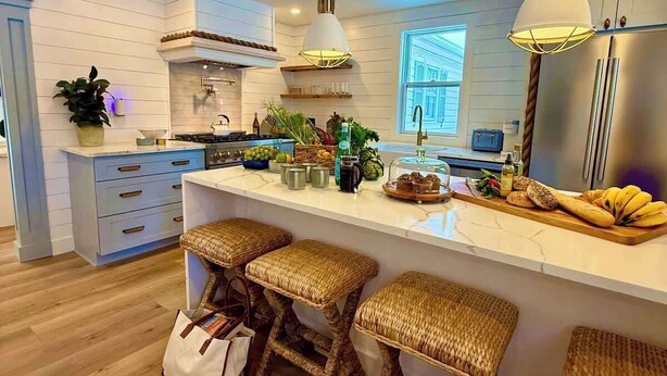 Een moderne keuken met een centraal eiland, barkrukken en hanglampen.
