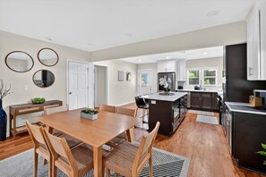 A modern kitchen with a central island, wooden dining table, and chairs. - Grove Park Haven Sleeps 12, Large Backyard (Atlanta)