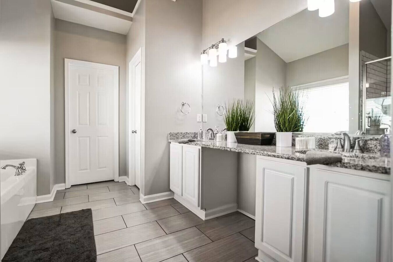 A modern bathroom with a walk-in shower, a vanity with a large mirror, and a granite countertop.