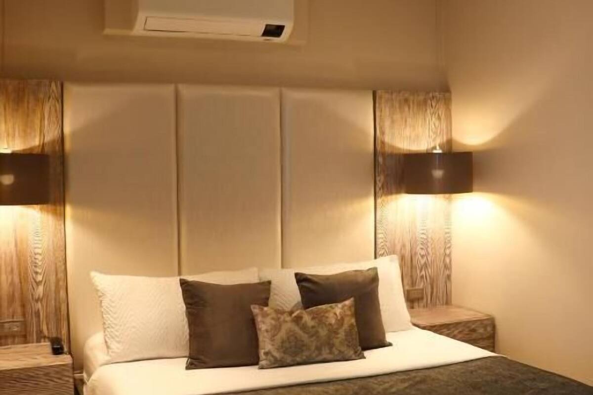 A bedroom with a bed, nightstands, a ceiling fan, and wall-mounted lighting.