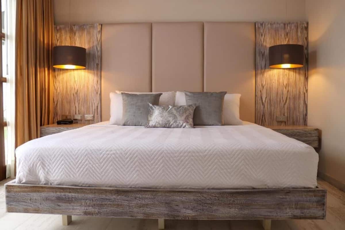 A bed with a herringbone quilt, two bedside lamps, and a wooden headboard.