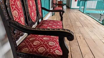 A wooden bench with red patterned upholstery in a corridor with teal accents and wooden flooring.