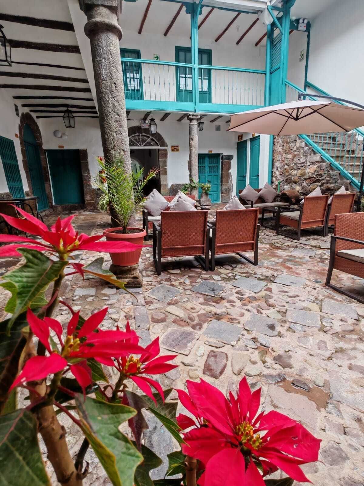 An outdoor seating area with stone flooring, wicker furniture, and potted plants.