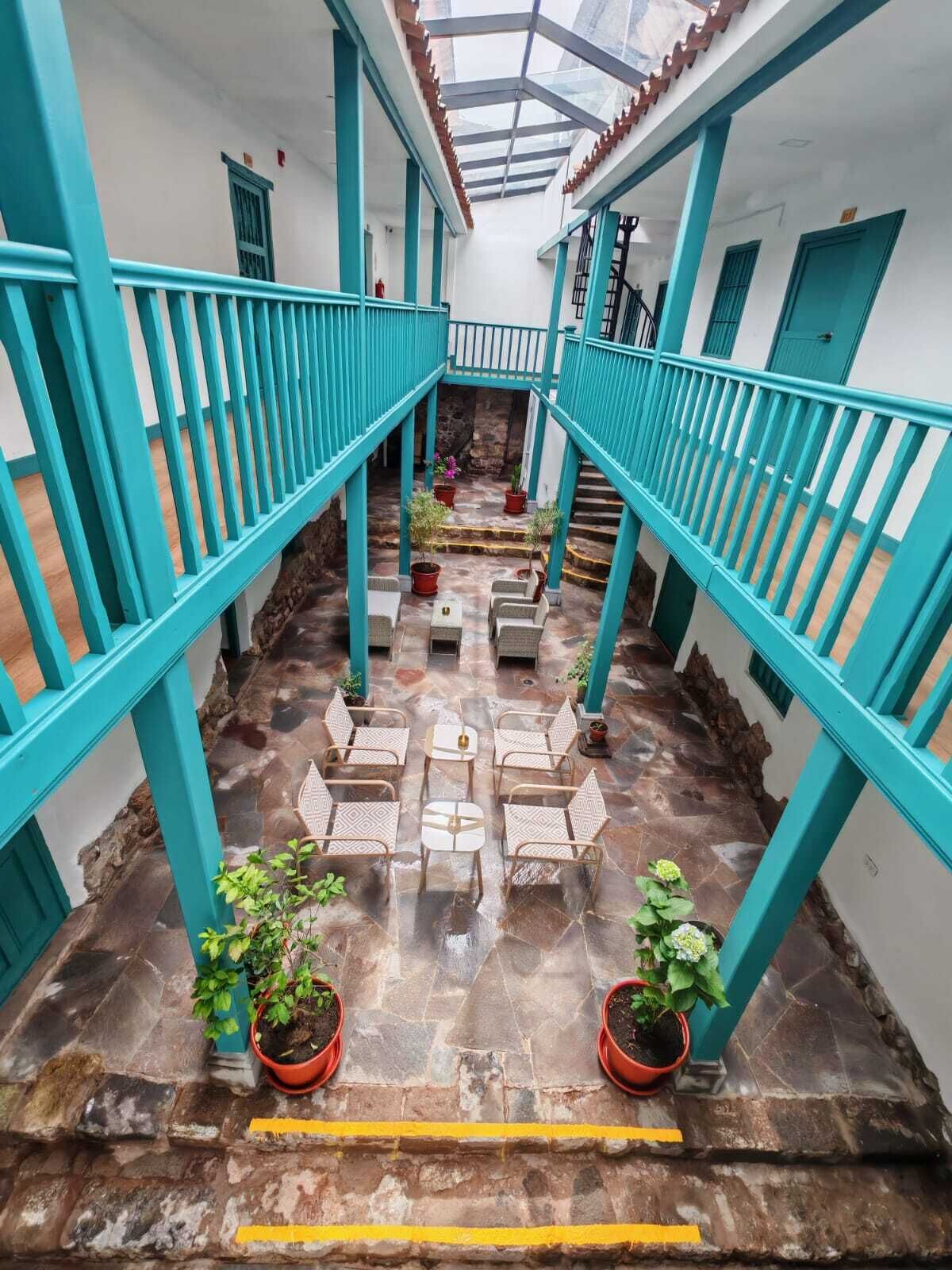 A courtyard with a central seating area, potted plants, and a staircase leading to an upper level.