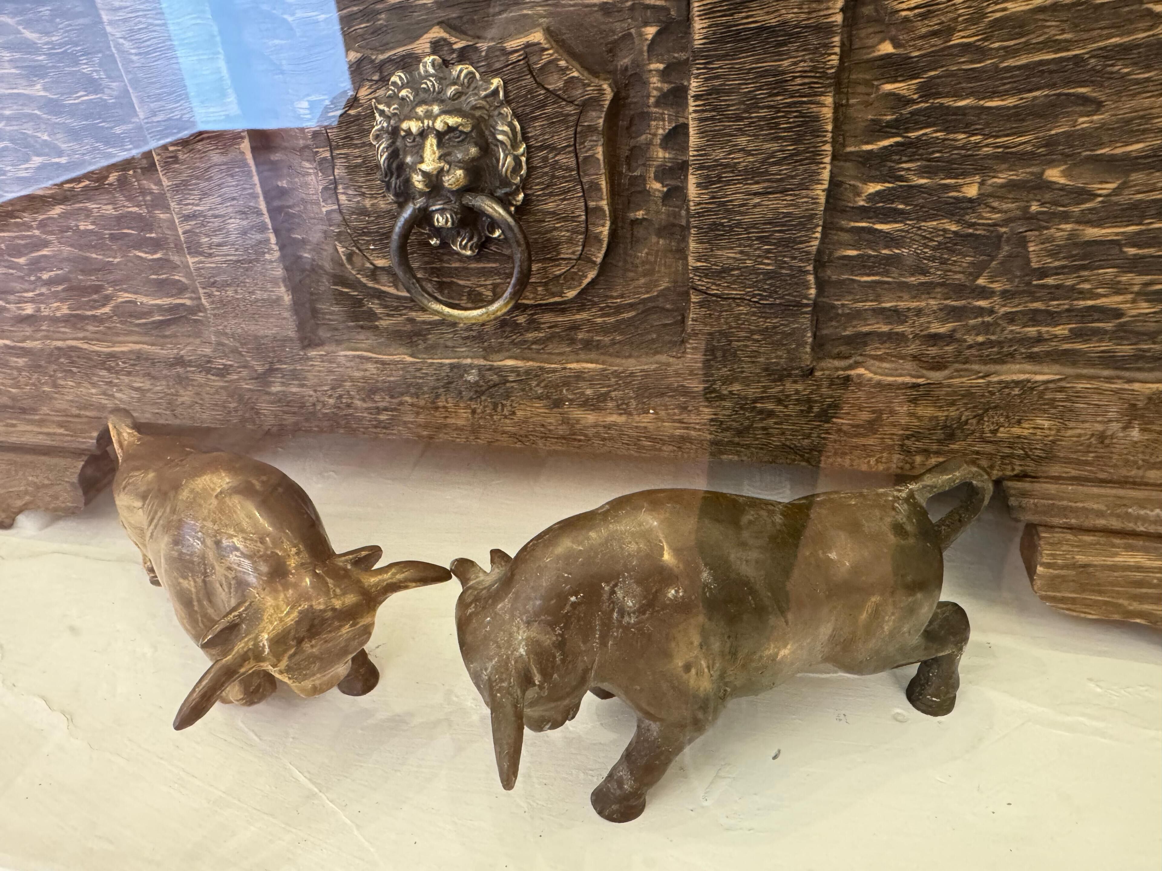 A wooden chest with a lion head lock and two pig figurines.