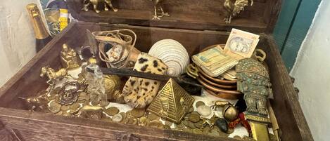 A wooden chest filled with various items including coins, jewelry, and decorative objects.