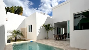 Une maison moderne dotée d’une piscine, d’un espace extérieur aménagé et offrant une vue sur un ciel dégagé.