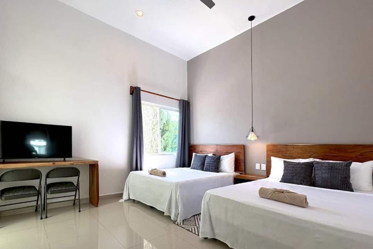 Een hotelkamer met twee bedden, een televisie en een bureau met stoelen.