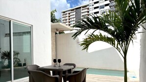 Une terrasse avec une table et des chaises, une petite piscine et un palmier.