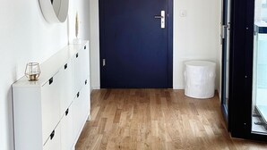 A hallway with a wooden floor, a white console with drawers, a dark blue door, and a round mirror on the wall. - Top modern Apartment near Novartis Campus (Basel)
