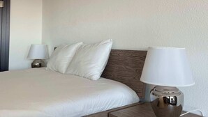 A neatly made bed with white linens, a wooden headboard, and a bedside lamp with a white shade. - Top modern Apartment near Novartis Campus (Basel)