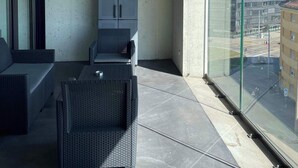 A balcony with a sofa, a small table, and a cabinet. - Top modern Apartment near Novartis Campus (Basel)