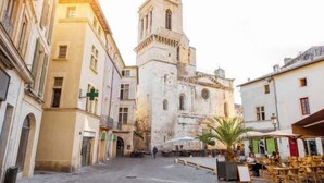 Une place historique, dominée par le clocher d’une église remarquable, avec des rues pavées et des espaces aménagés pour s’asseoir en plein air.