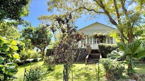 A house with a front porch, surrounded by lush greenery and a clear sky. - Le Refuge, Old Creole Villa with Swimming Pool (La Montagne)