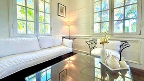 A room with a white sofa, a glass coffee table, and a floor lamp. - Le Refuge, Old Creole Villa with Swimming Pool (La Montagne)