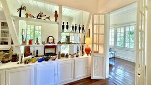 A spacious room with high ceilings, a long white cabinet with various decorative items, and a large window providing natural light. - Le Refuge, Old Creole Villa with Swimming Pool (La Montagne)