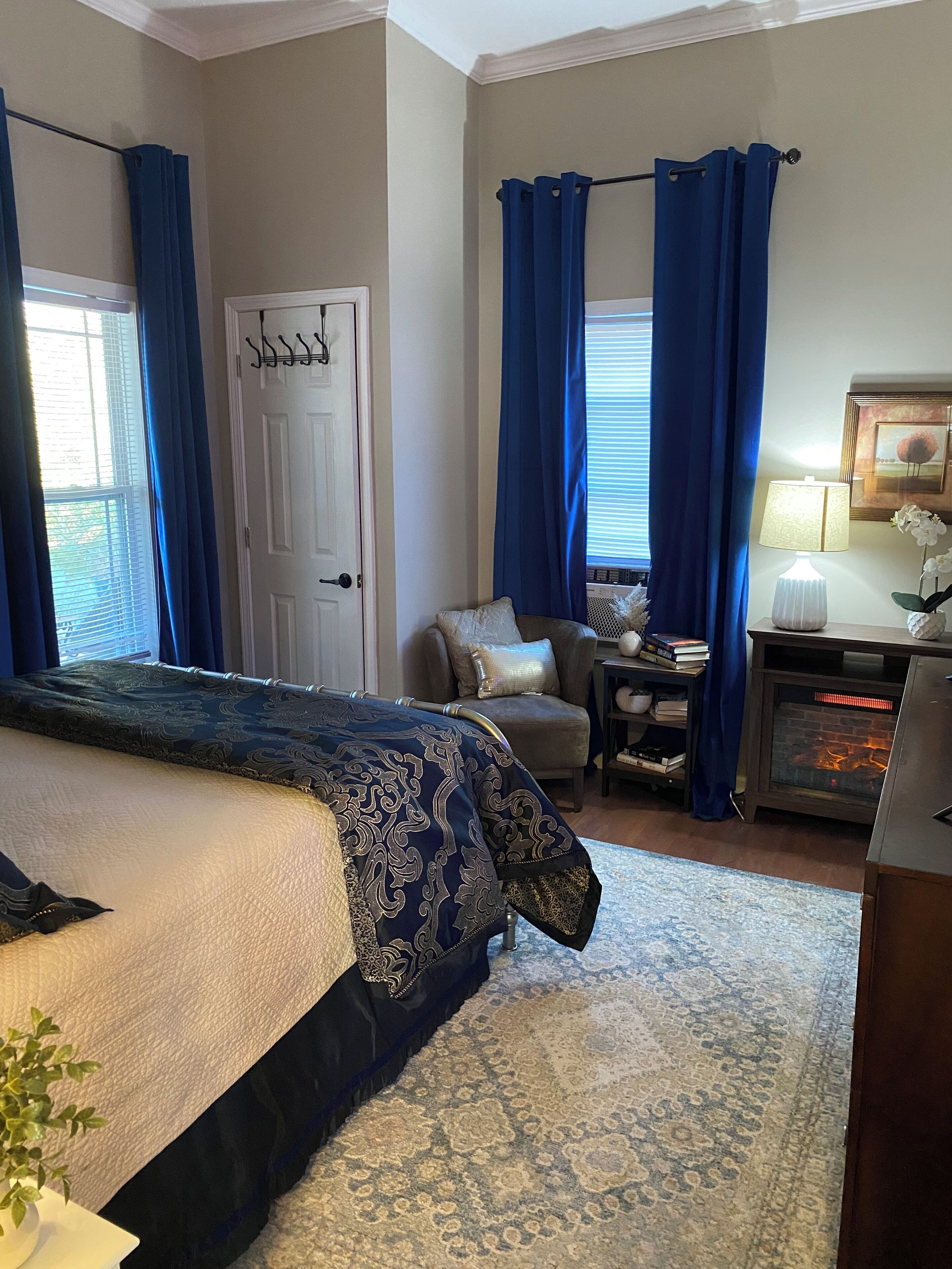 Une chambre à coucher avec un lit, une chaise, une petite table, une lampe et une cheminée.
