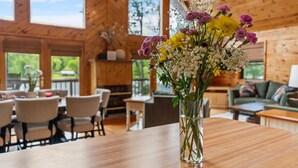 Un interno in legno con un tavolo da pranzo, sedie, un divano e un vaso di fiori.