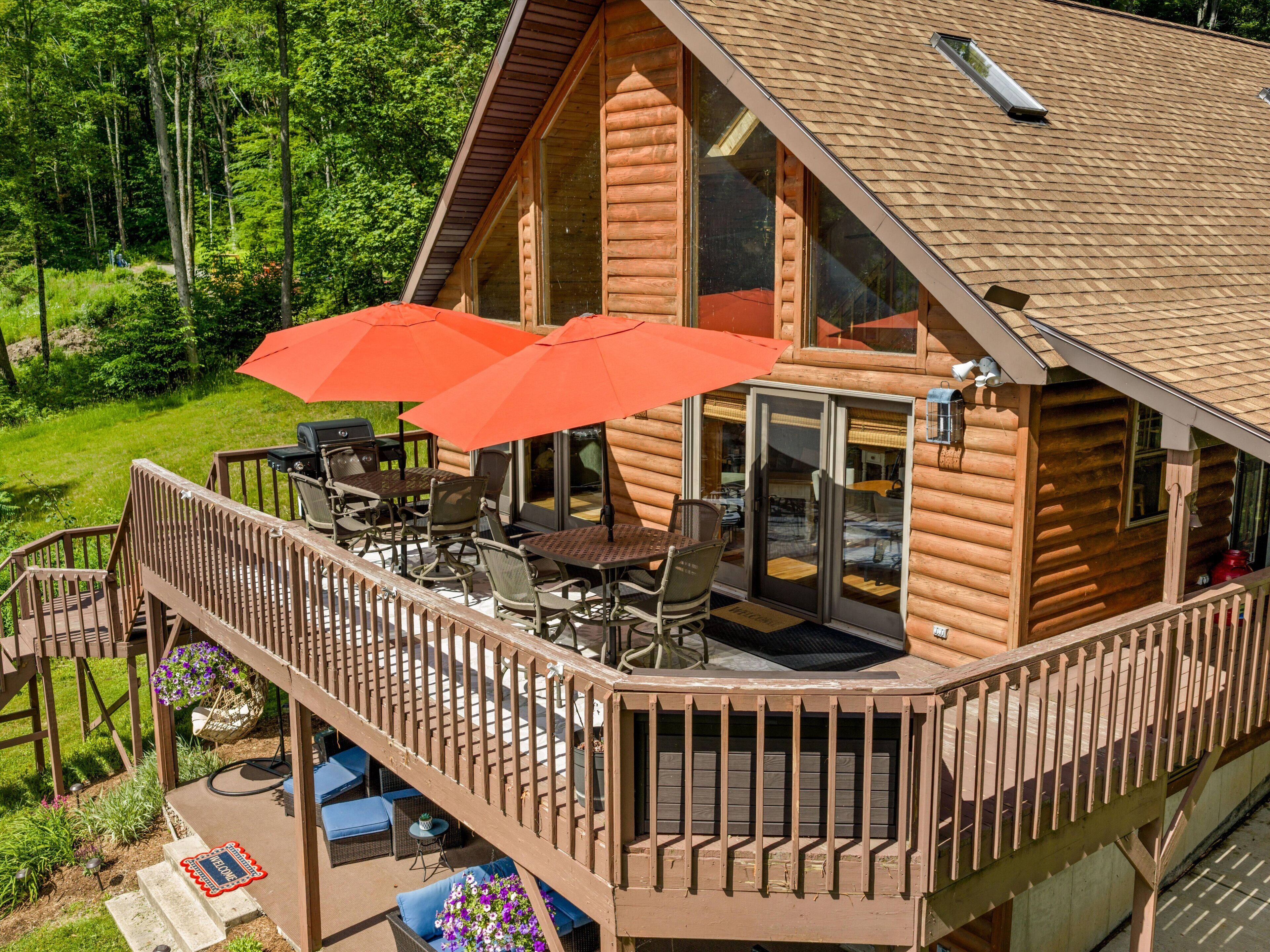 A log cabin with a deck, outdoor seating, and a large window.