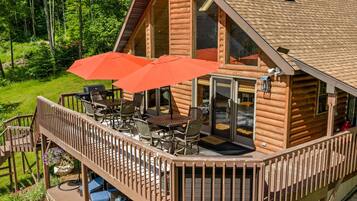 A log cabin with a deck, outdoor seating, and a large window.